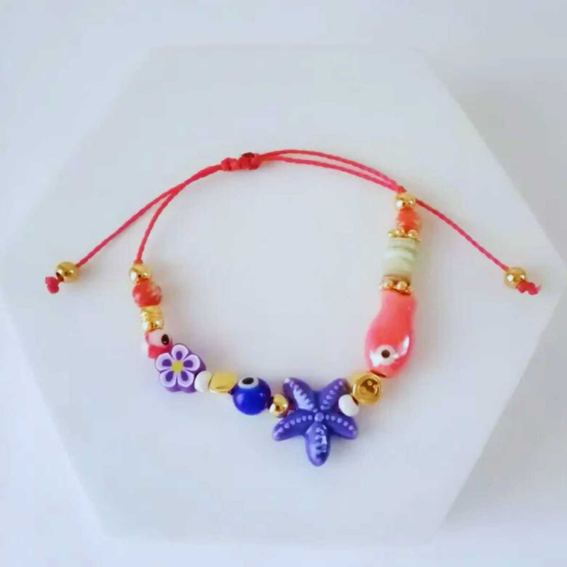 Pulsera "Ocean Bloom" con charms de estrella de mar, flor, pez y ojo turco, en tonos vibrantes.